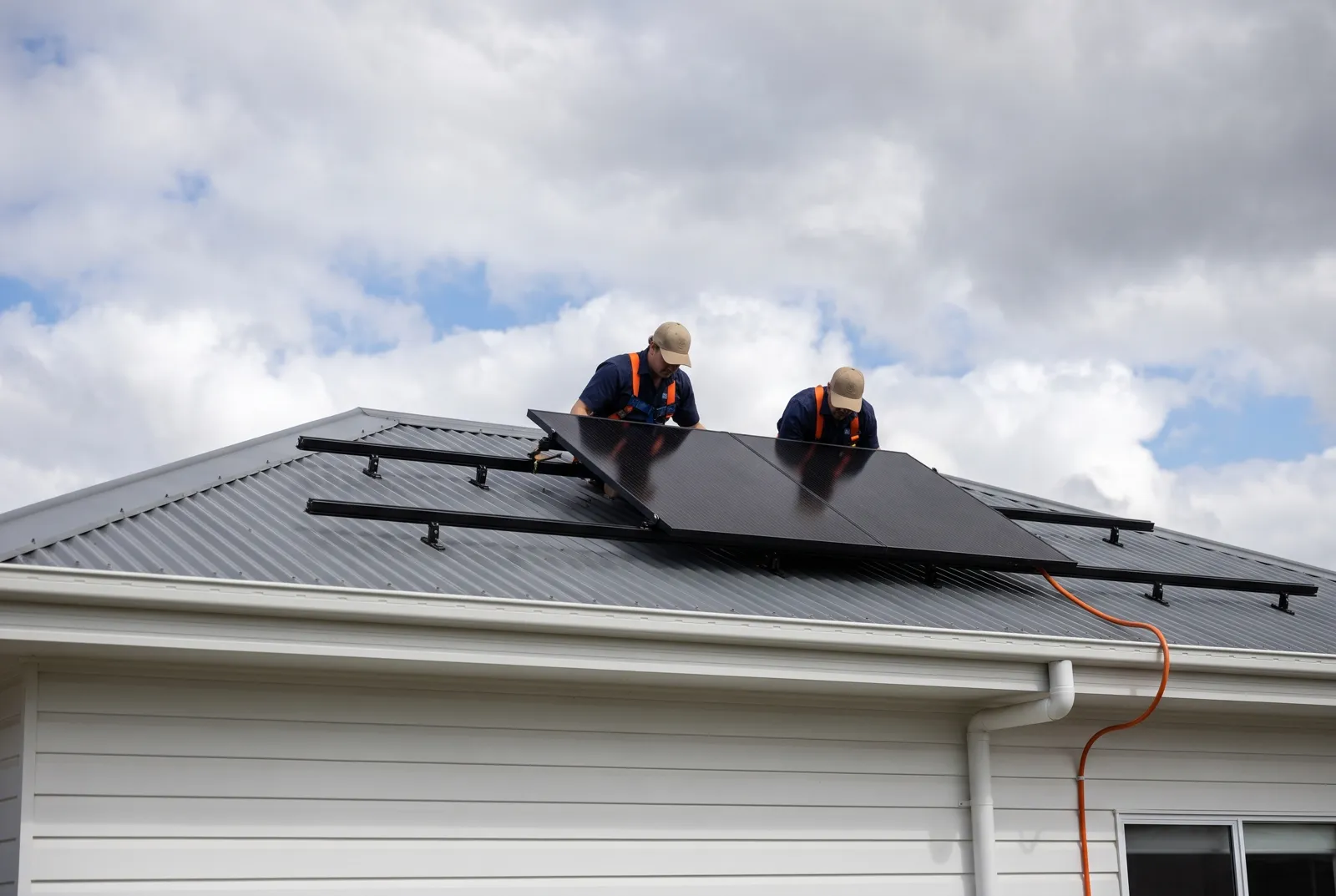 The crew carrying the first solar panel across a roof