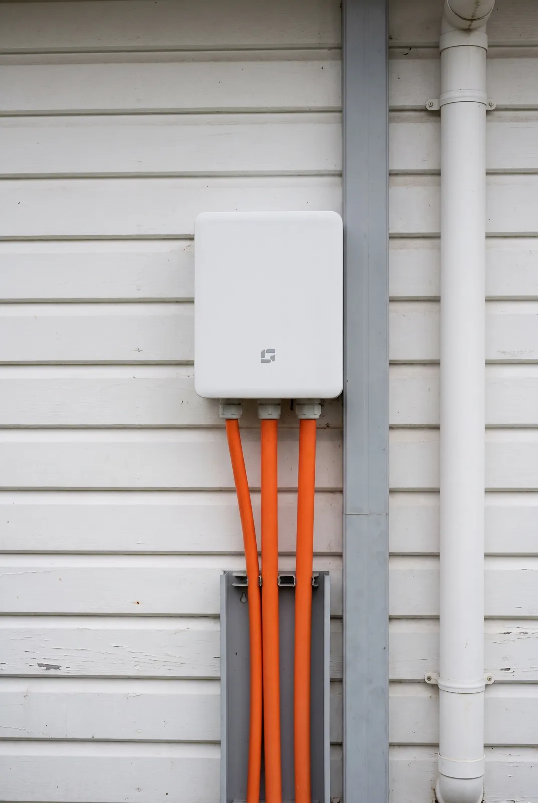 A gateway on a wall with orange conduit running down