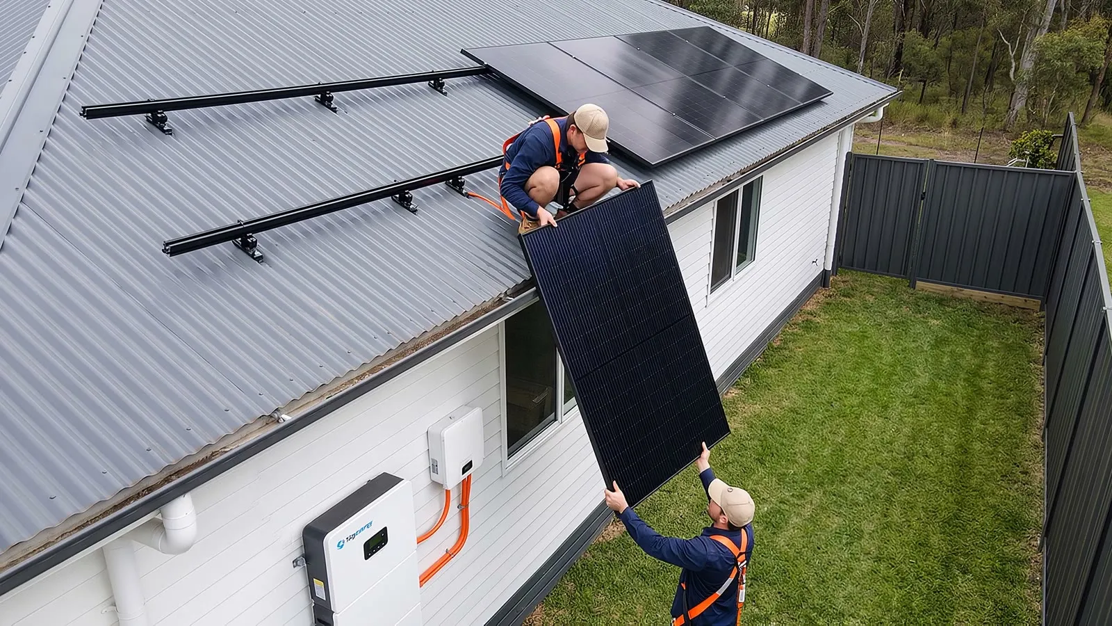 Two installers fitting solar panels to a house roof